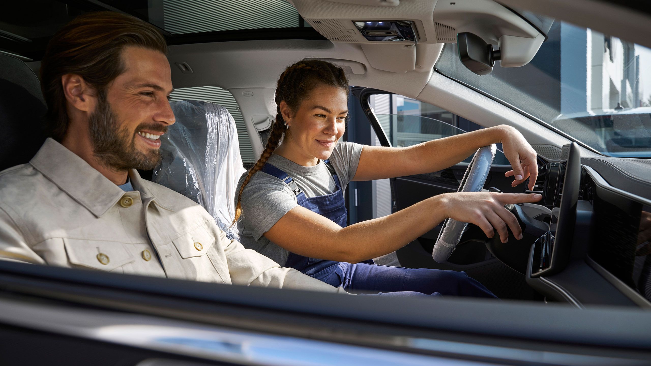 Zamestnanec servisu VW a muž sediaci v aute VW, ktorý sa pozerá na infotainment systém kvôli aktualizáciám softvéru.