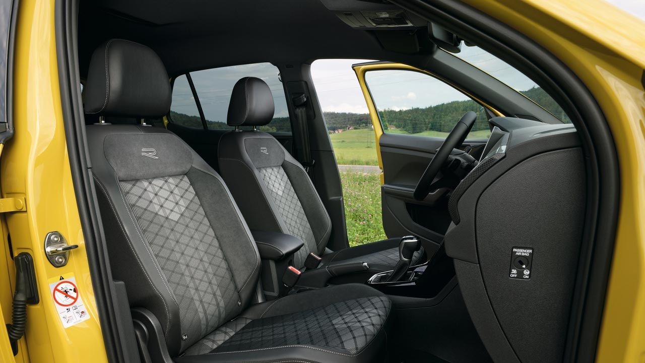 "Pohľad cez dvere predného spolujazdca žltého VW T-Cross s voliteľnými komfortnými sedadlami Sport a stredovou lakťovou opierkou."