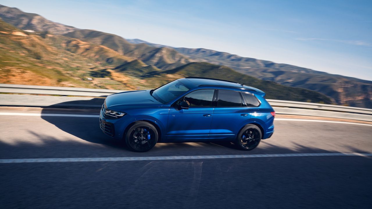 VW Touareg R eHybrid v rýchlosti na horskej ceste. V pozadí sú rozostrené hory a kopce.