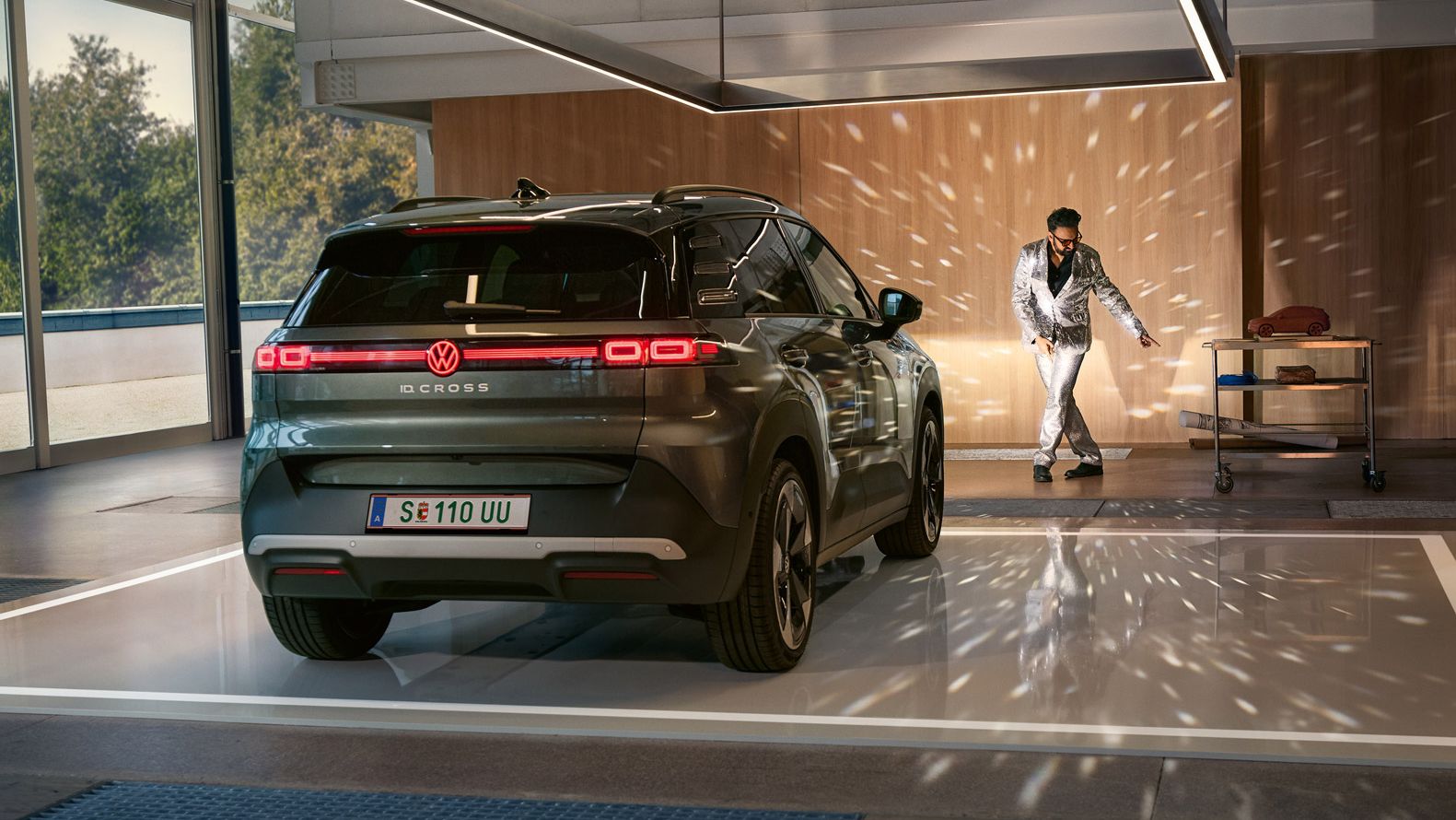VW ID. Cross stojí v showroome so zapnutými svetlami a osvetľuje tancujúcího muža v trblietavom obleku.