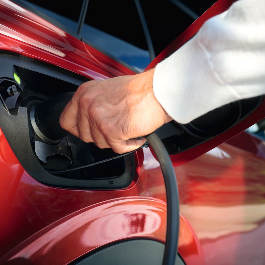 Nejaká osoba zapája nabíjací kábel do vozidla VW.