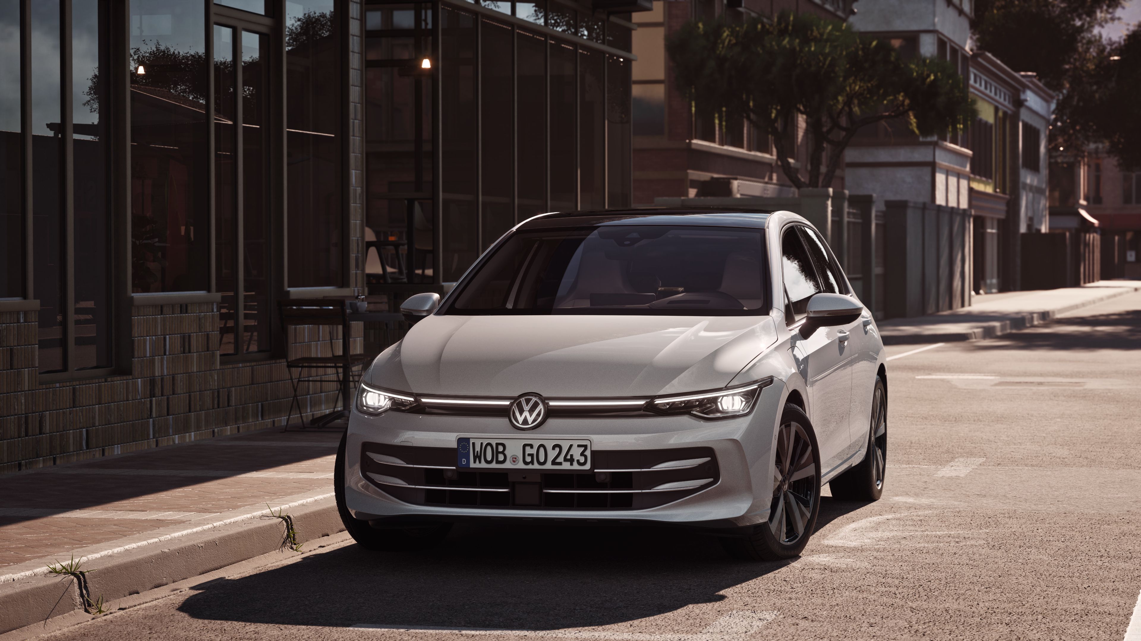 Na ceste pri chodníku pred reštauráciou v meste parkuje biely VW Golf. 