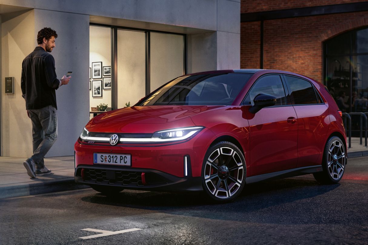 Človek prechádza okolo červeného VW ID. Polo GTI, ktoré parkuje pred modernou budovou.