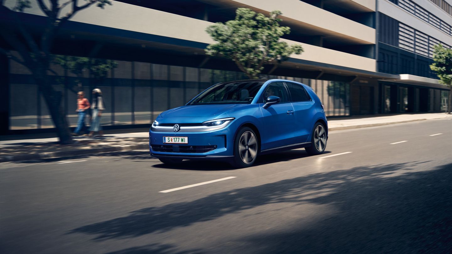 Modrý VW ID. Polo Style prechádza mestom so zelenými stromami pozdĺž cesty.
