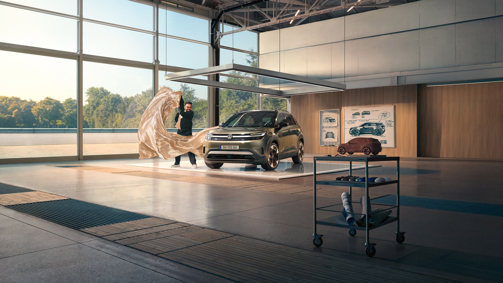 Muž vytiahne veľkú látku zo zeleného VW ID. Cross, ktorý stojí v minimalistickom dizajnérskom štúdiu.