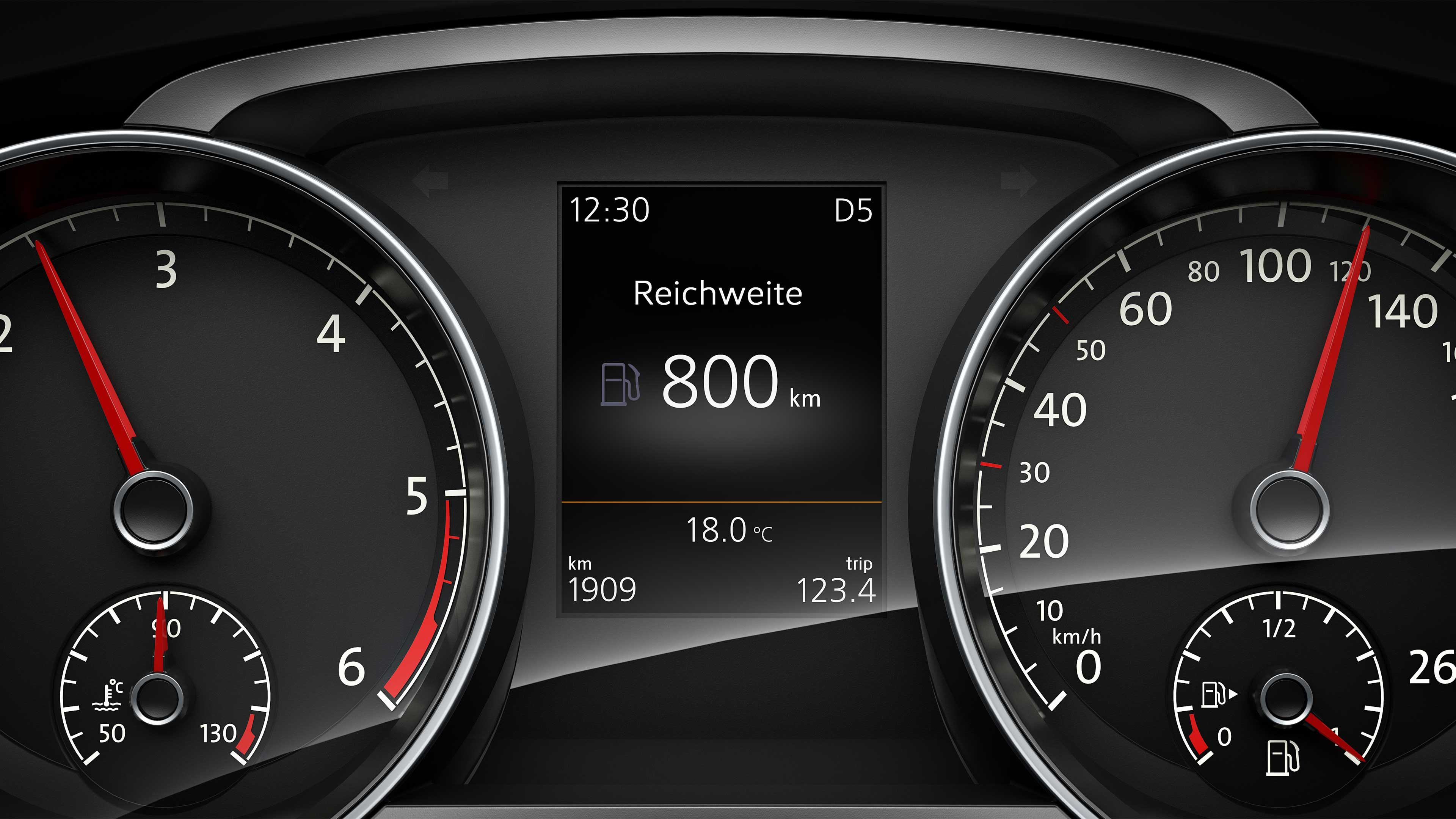 Digitálny displej palubného počítača automobilu zobrazuje dojazd 800 km a aktuálnu teplotu 18°C von. Naľavo a napravo od displeja sú analógové ukazovatele tachometra a otáčkometra..