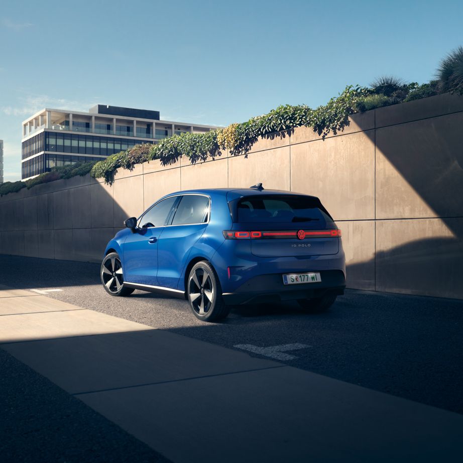 Modrý VW ID. Polo Style stojí na kraji cesty pri betónovej stene.