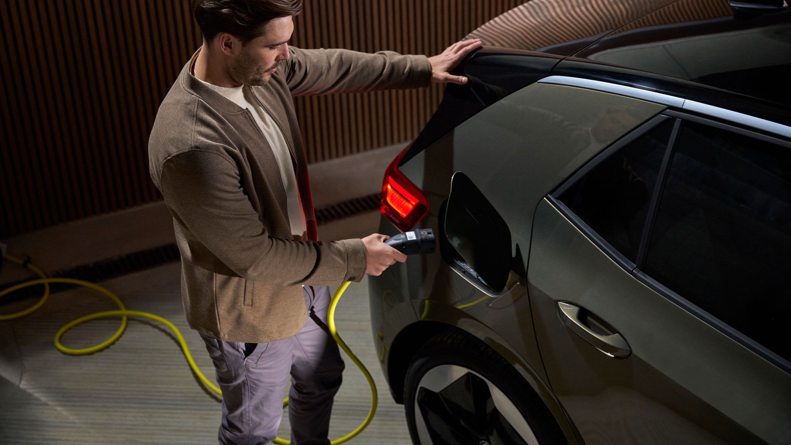 Muž nabíja vozidlá VW ID. Model pomocou nabíjacieho kábla VW príslušenstva