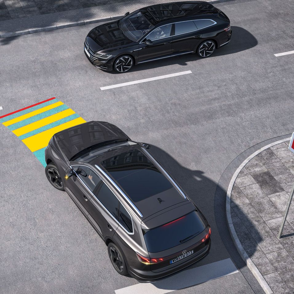 VW asistent rozpoznania križovatky znázornený modro-žlto-červenou grafikou na ceste. Dve vozidla na križovatke, každé v inom jazdnom pruhu, sa približujú a hrozí im kolízia. 