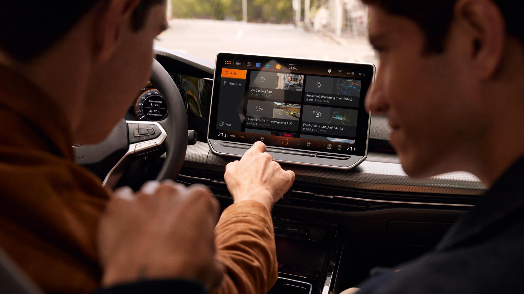 Pohľad do interiéru VW Golf s výhľadom na displej. Muži na sedadle vodiča a spolujazdca ovládajú systém infotainment.