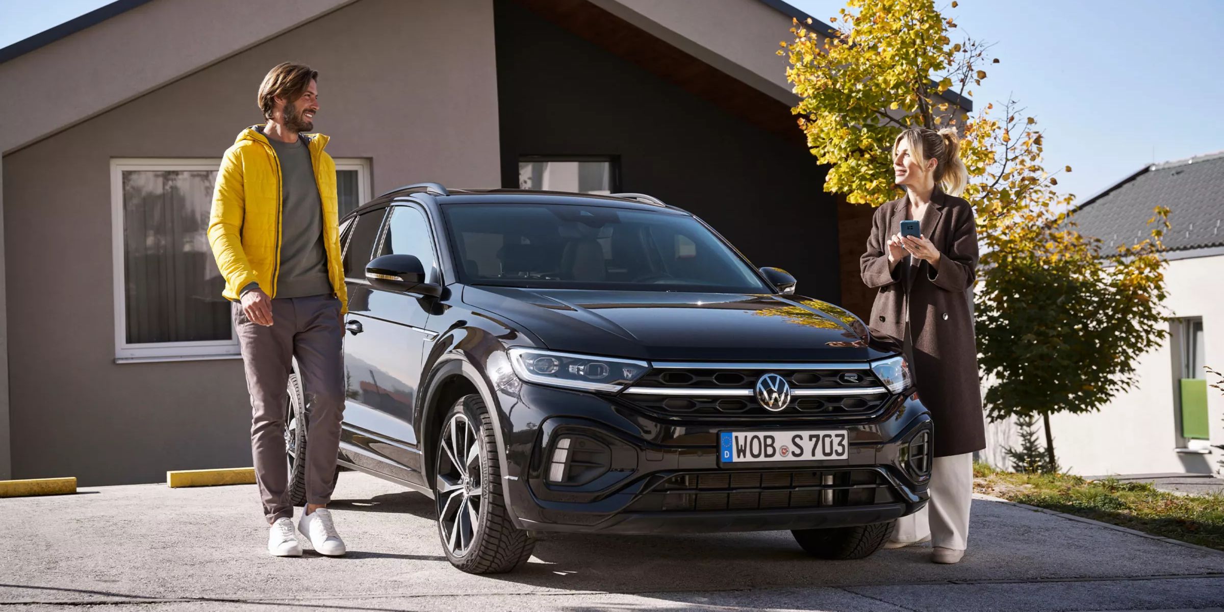Žena so smartfónom a muž vedľa auta VW