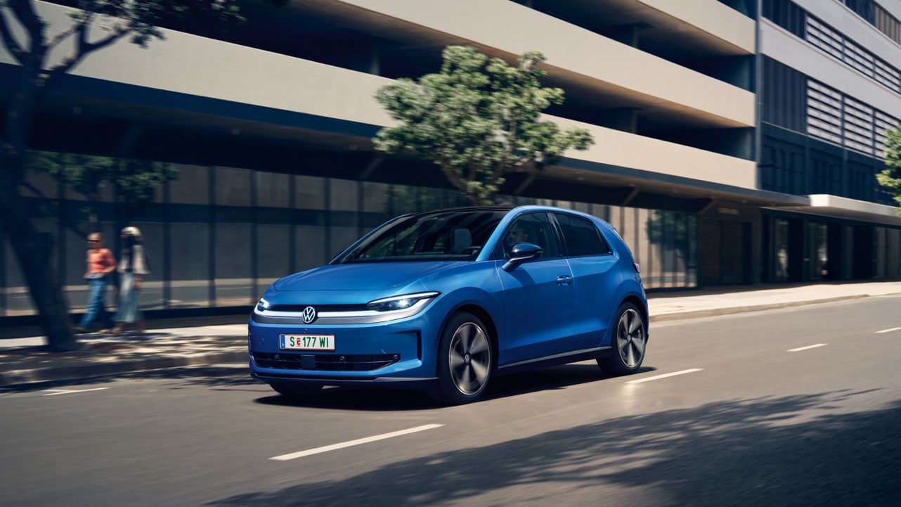 Modrý VW ID. Polo Style prechádza mestom so zelenými stromami pozdĺž cesty.