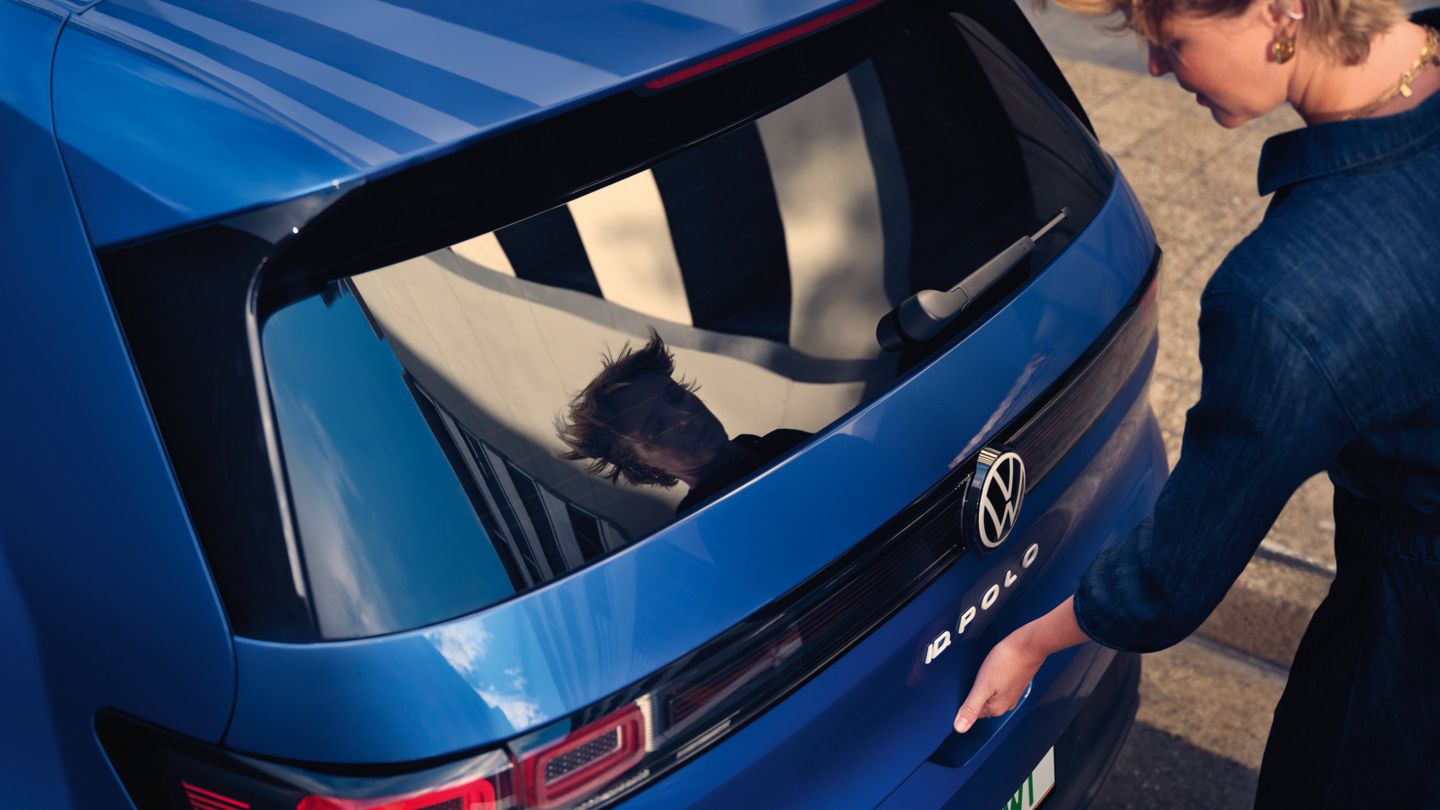 Žena otvára zadné dvere modrého VW ID. Polo Style.