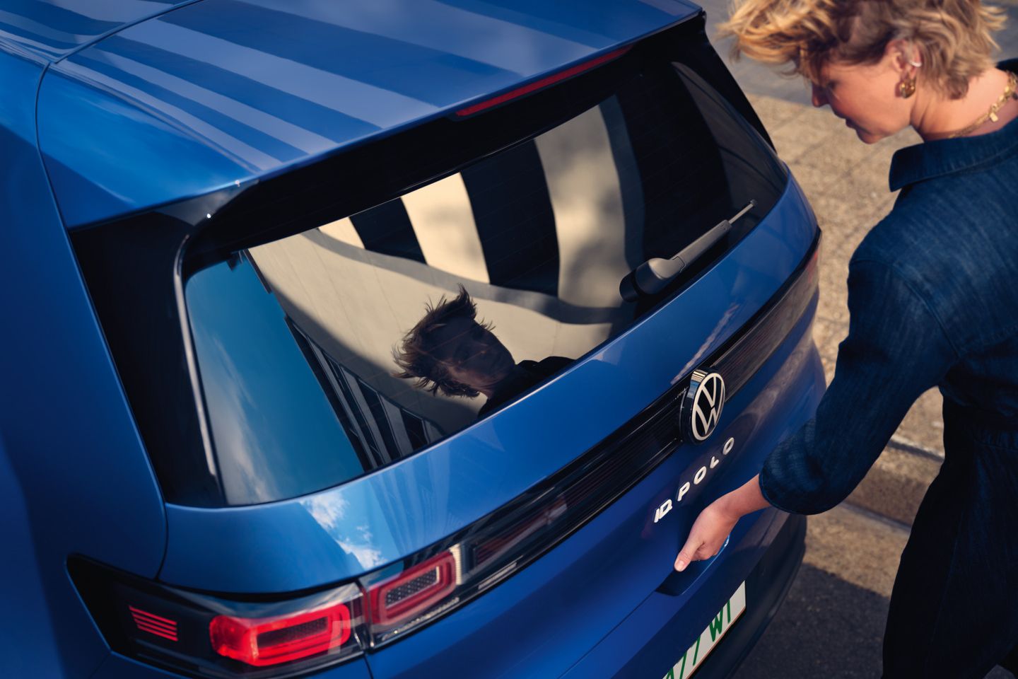Žena otvára zadné dvere modrého VW ID. Polo Style.