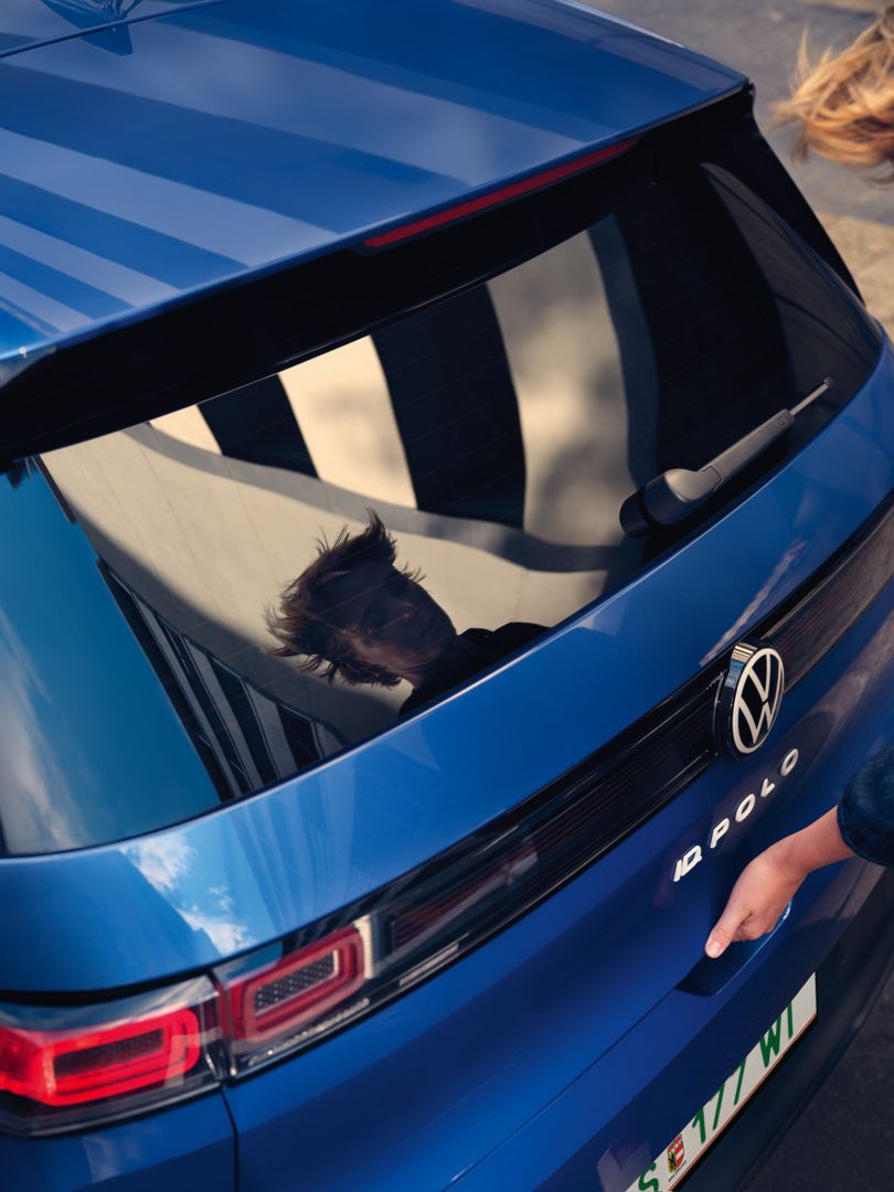 Žena otvára zadné dvere modrého VW ID. Polo Style.