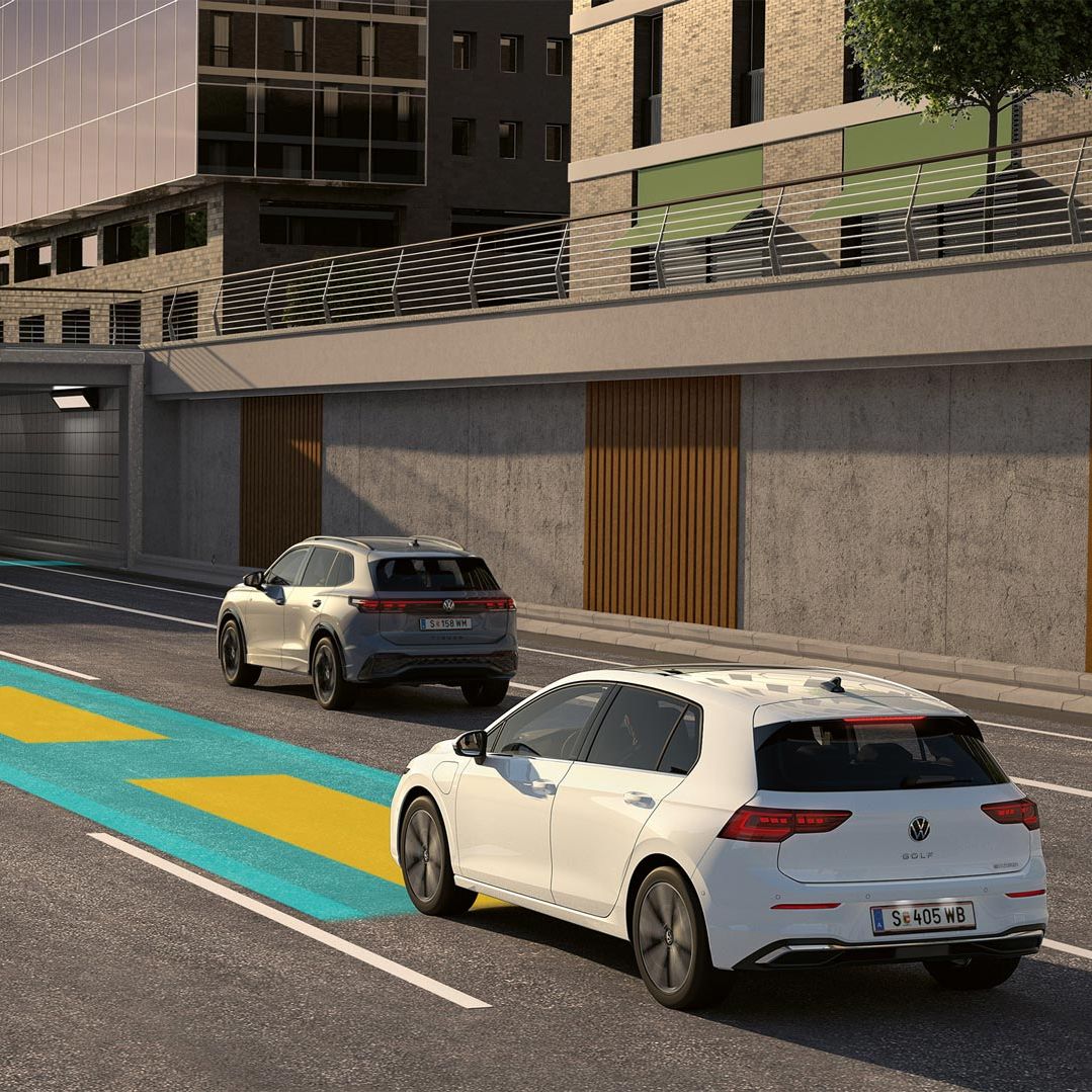 Biely VW Golf jazdí v premávke s využitím voliteľného asistenčného systému, ktorý je schematicky znázornený na obrázku. V pozadí vidieť mestské výškové budovy.