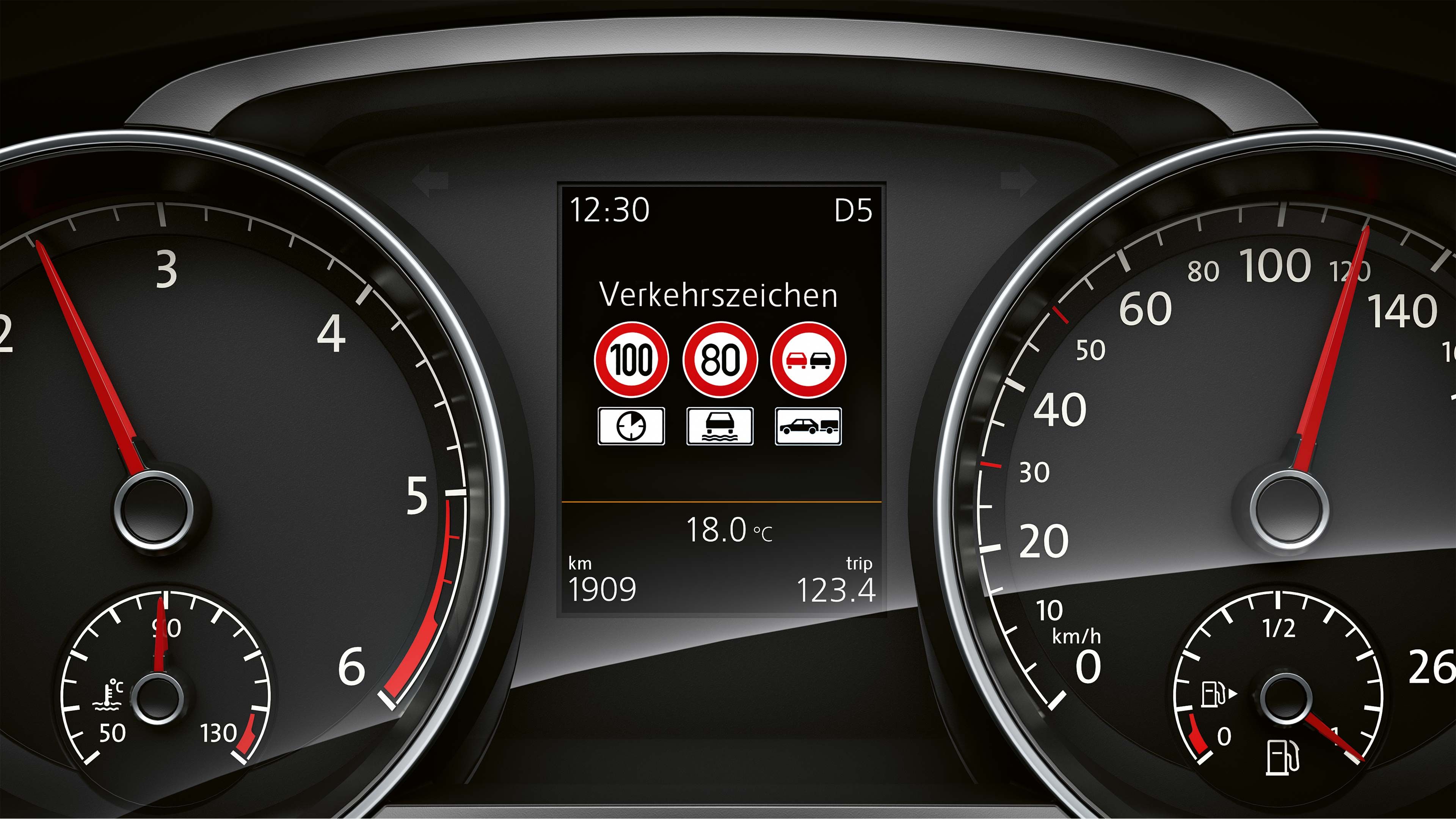 Prístrojový panel automobilu s dvoma veľkými ručičkovými ukazovateľmi, ktoré zobrazujú rýchlomer a otáčkomer. Stredový displej ukazuje dopravné značky a aktuálnu teplotu.