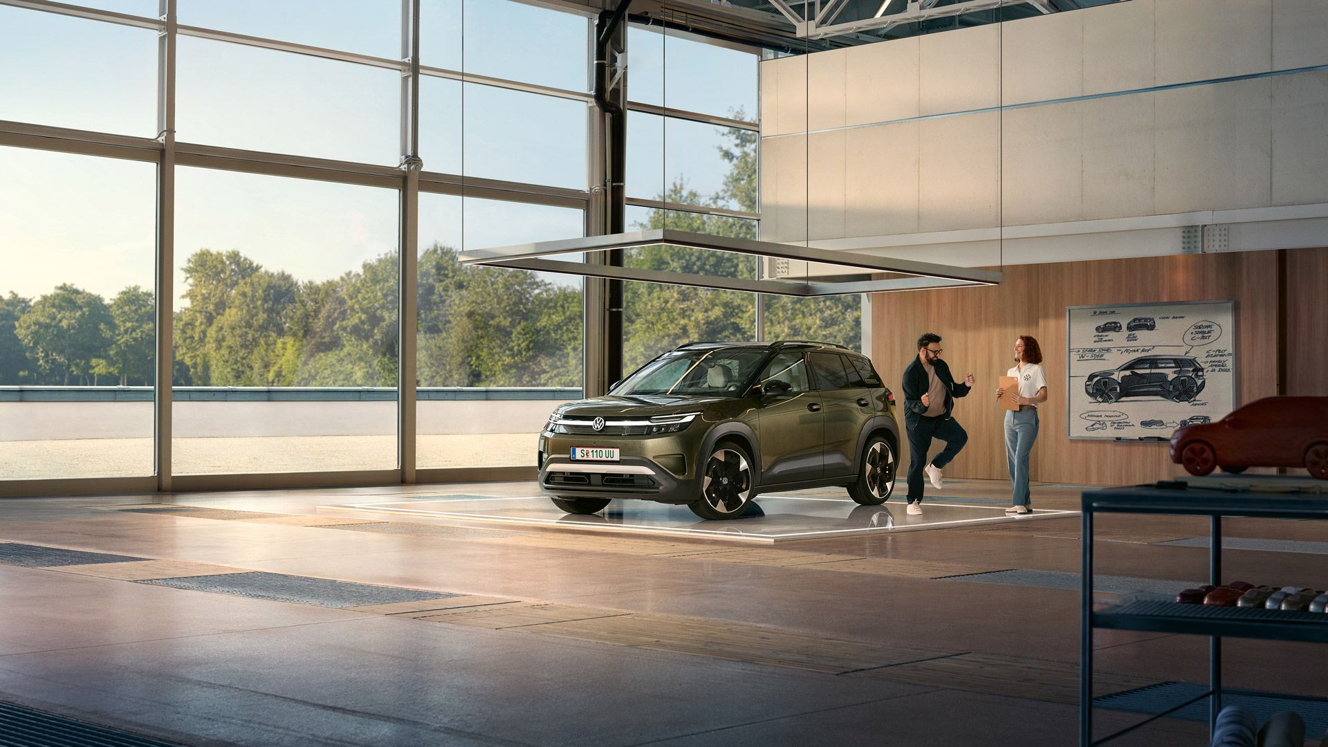 VW ID. Cross je zaparkovaný v minimalistickom dizajnérskom štúdiu, vedľa poskakuje neho nadšený muž a rozpráva sa s inžinierom.