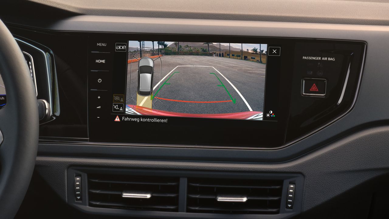 Cúvacia kamera vo VW Taigo. Pohľad na displej infotainment systému, na obrazovke vidieť okolie za vozidlom s pomocnými líniami plus grafiku vozidla z vtáčej perspektívy.