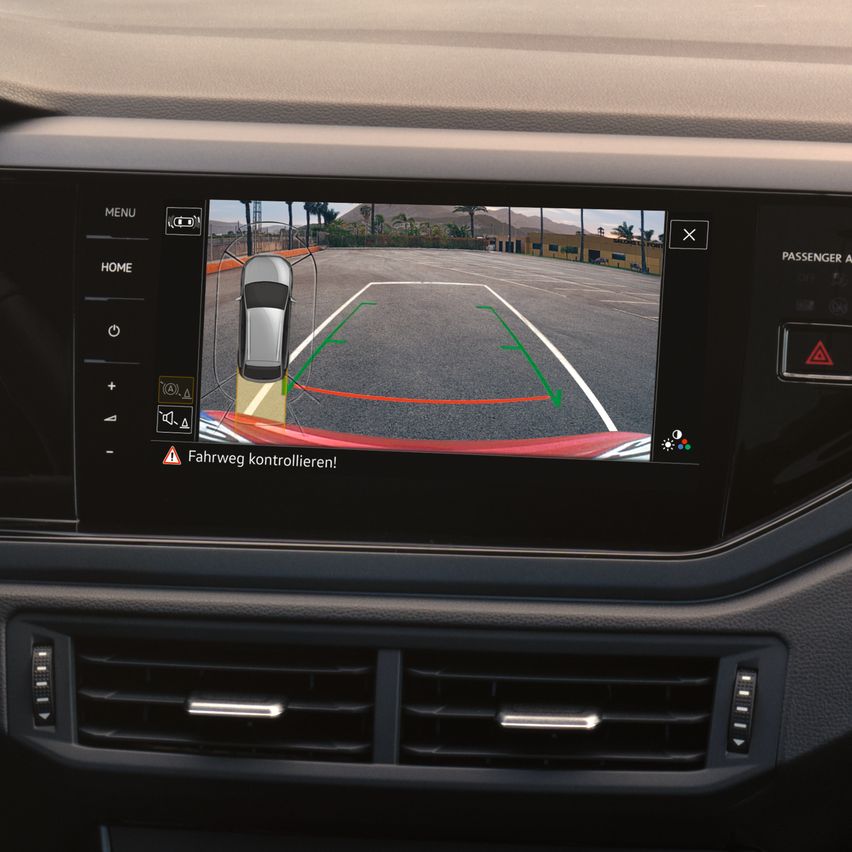 Cúvacia kamera vo VW Taigo. Pohľad na displej infotainment systému, na obrazovke vidieť okolie za vozidlom s pomocnými líniami plus grafiku vozidla z vtáčej perspektívy.