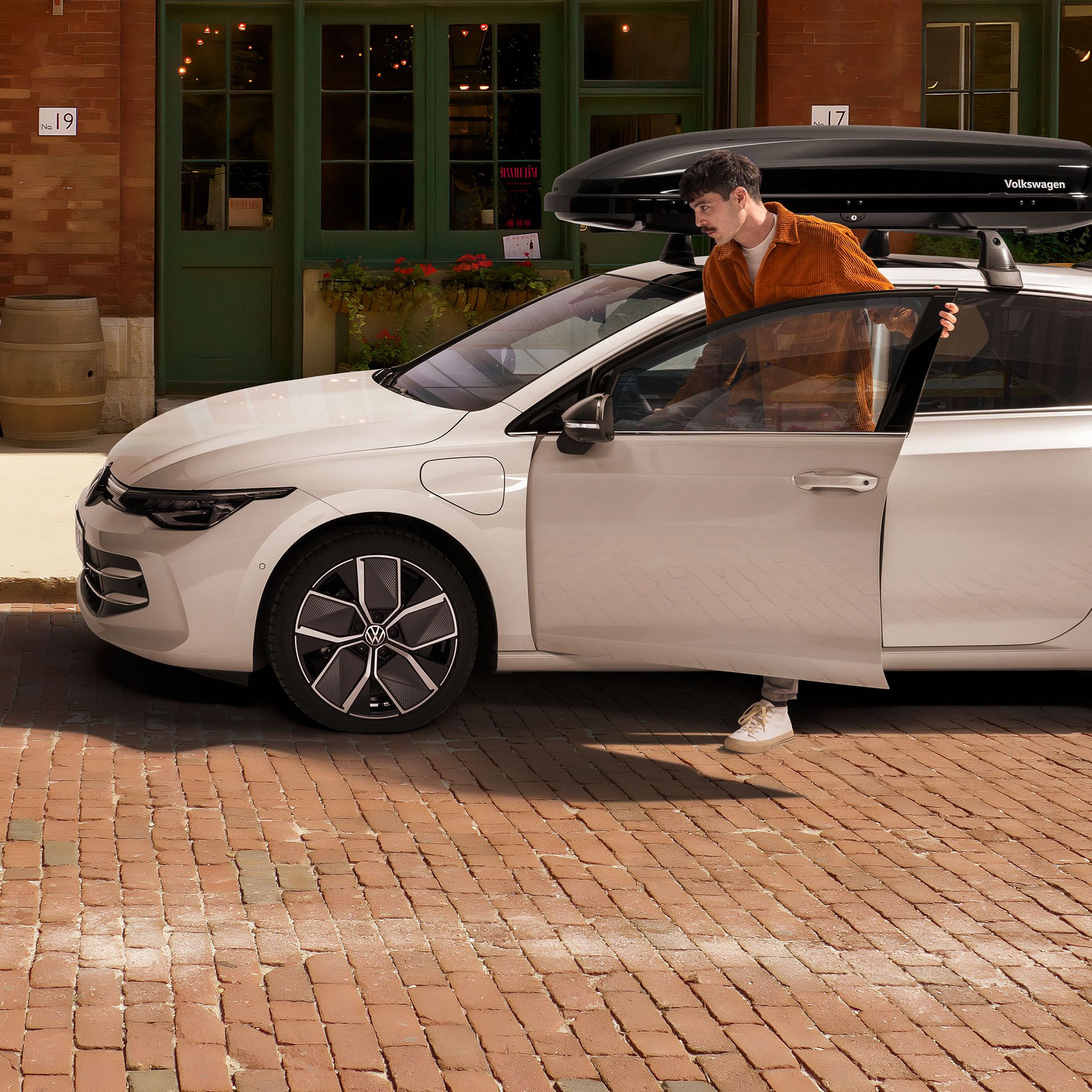 Muž nastupuje do VW Golf so strešným boxom, vedľa neho je VW Golf Variant
