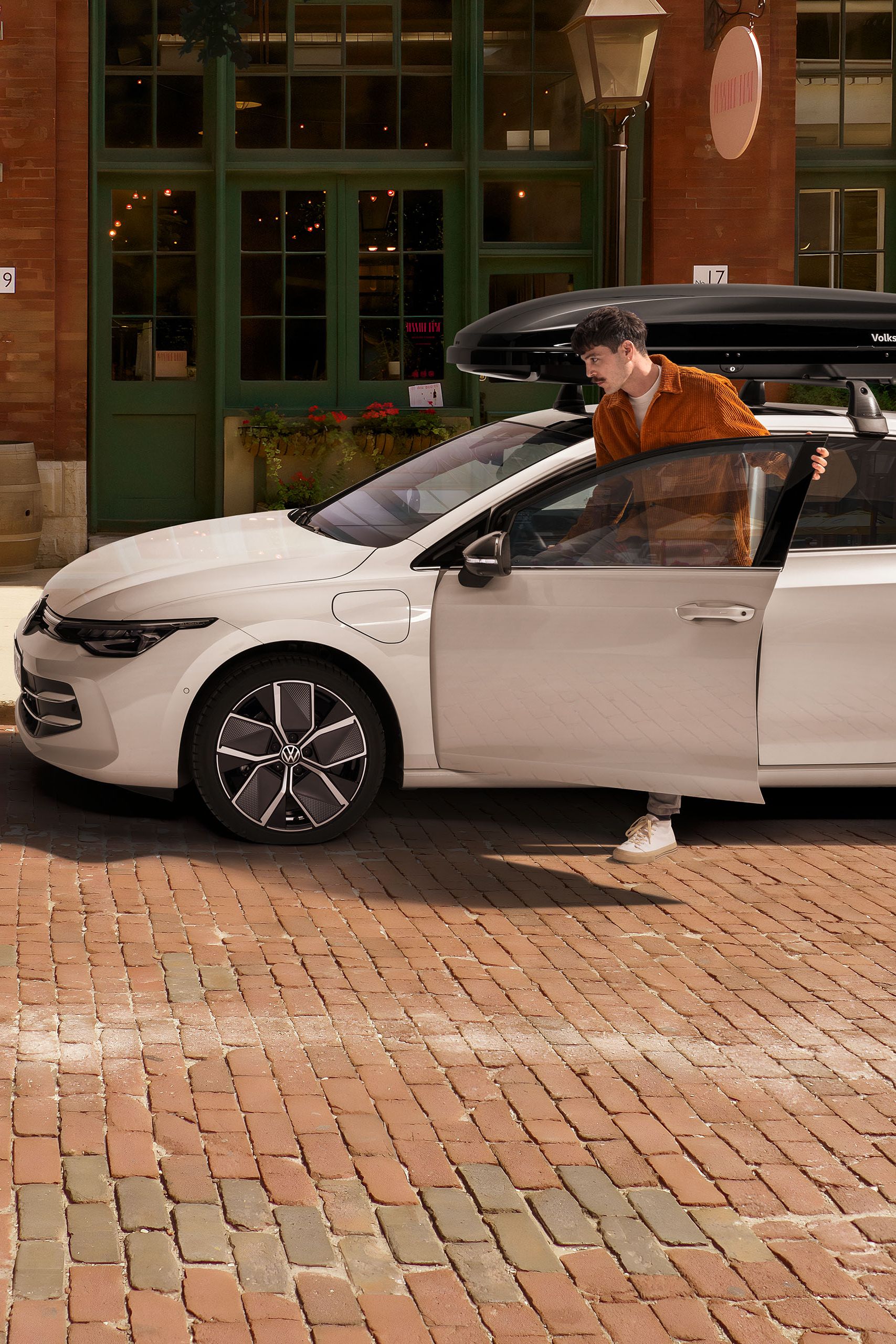 Muž nastupuje do VW Golf so strešným boxom, vedľa neho je VW Golf Variant