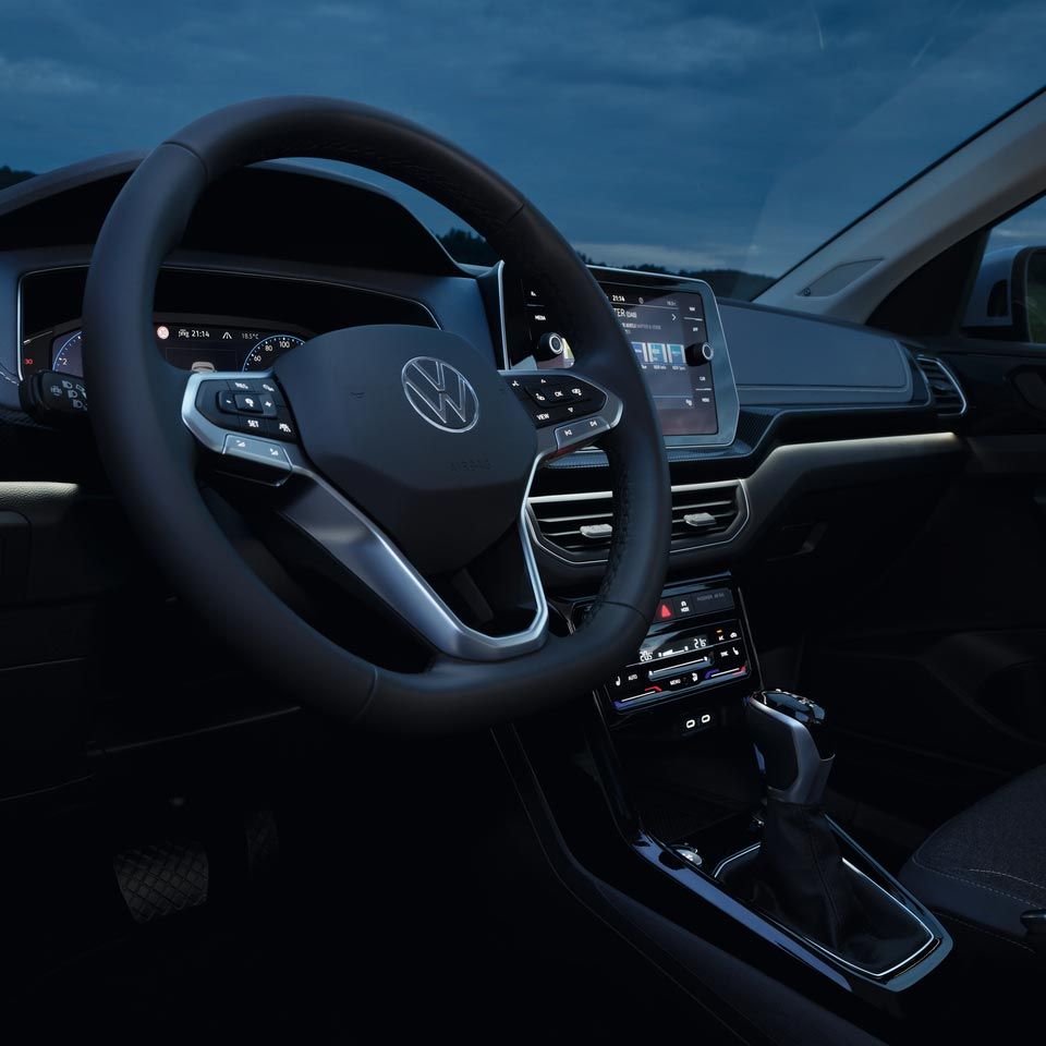 Detailný pohľad na vnútorný priestor vodiča VW T-Cross v noci so zameraním na biele ambientné osvetlenie