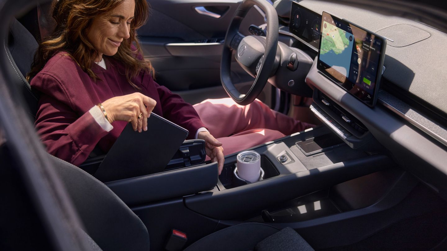 Žena ukladá tablet do stredovej konzoly s opierkou v tvare motýľa vo vozidle VW ID.3 Neo