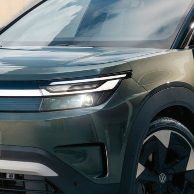 Zelený VW ID. Cross stojí pred modernou sklenenou budovou na betónovom povrchu.