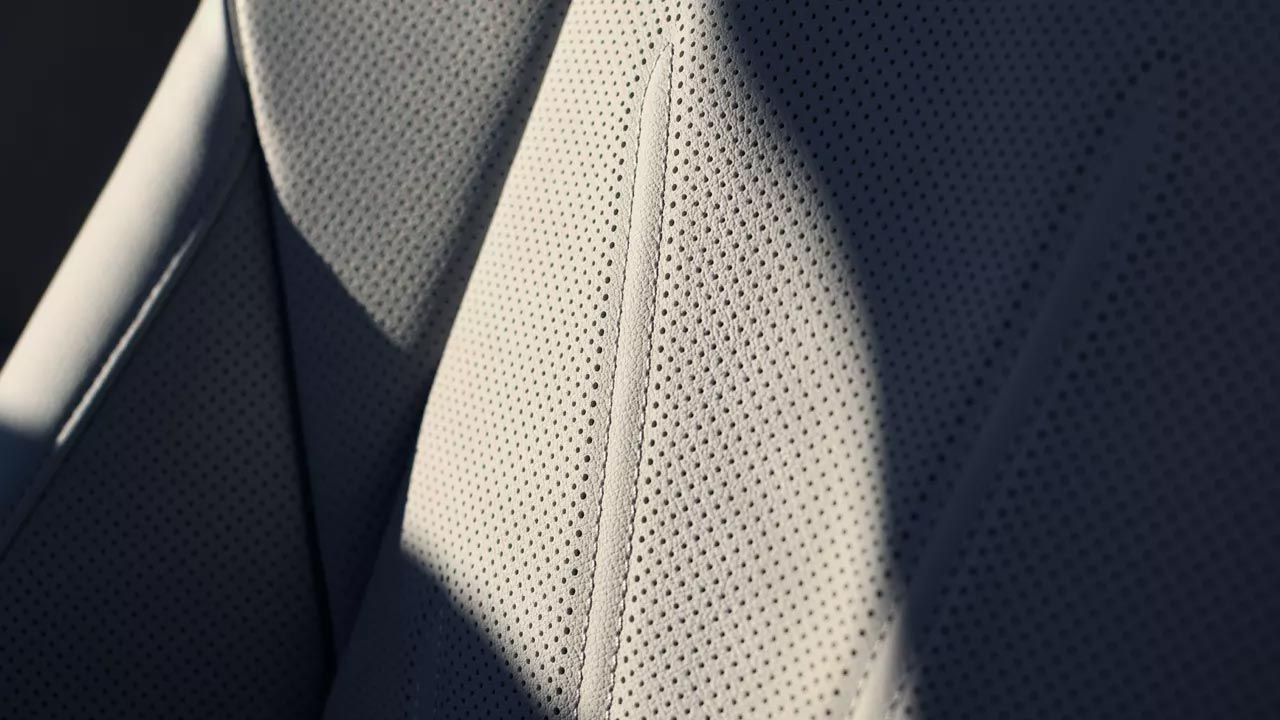 Detail šedého perforovaného koženého čalúnenia sedadla.