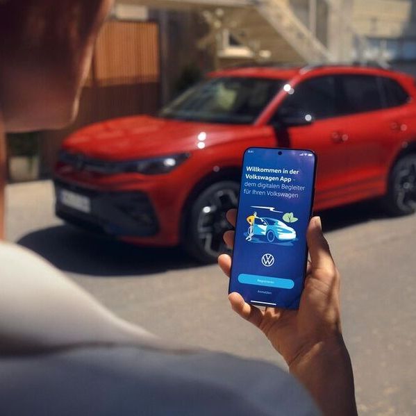 Muž so smartfónom v ruke, na ktorého displeji je zobrazená aplikácia Volkswagen.