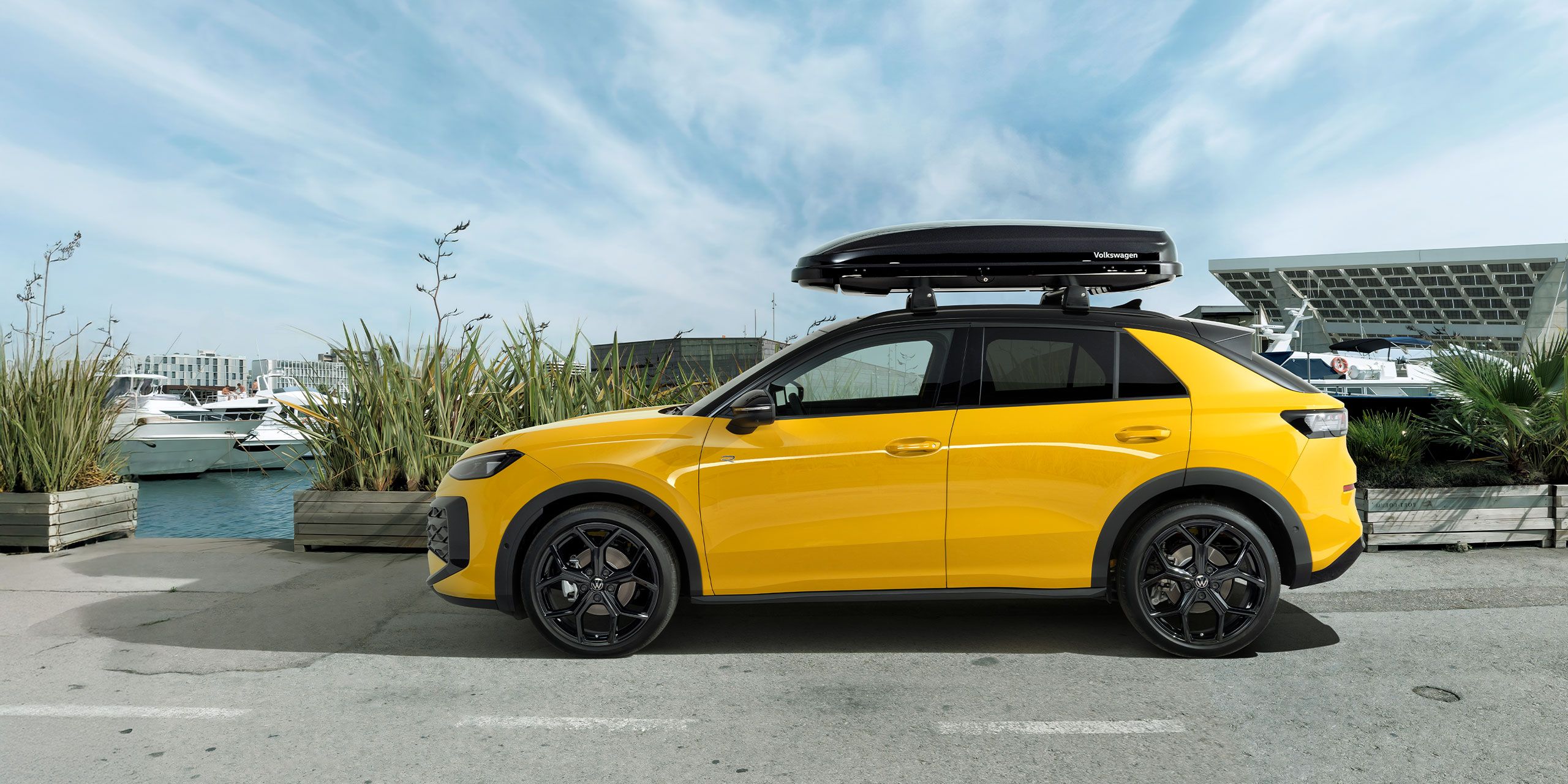 Žltý VW T-Roc so strešným boxom zaparkovaný na ceste – príslušenstvo T-Roc