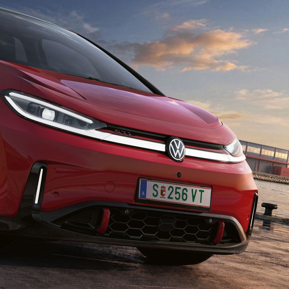 [AI-modified] – Detail predných partií zaparkovaného červeného VW ID.3 GTI so zapnutými svetlometmi a podsvieteným logom.