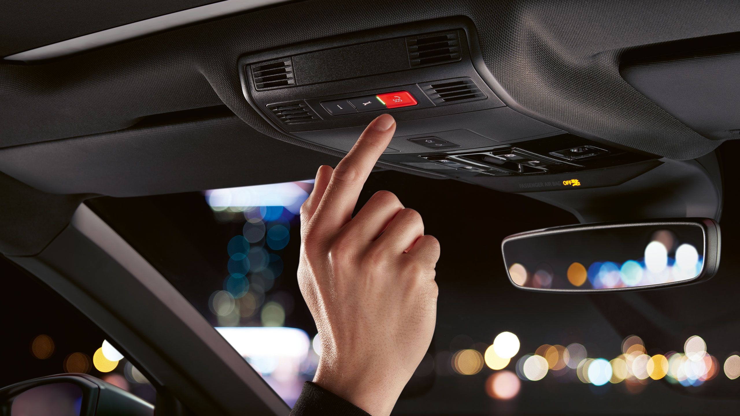 Detailný záber vo vozidle Volkswagen, kde sa ruka chystá stlačiť červené tlačidlo Volanie pri poruche.