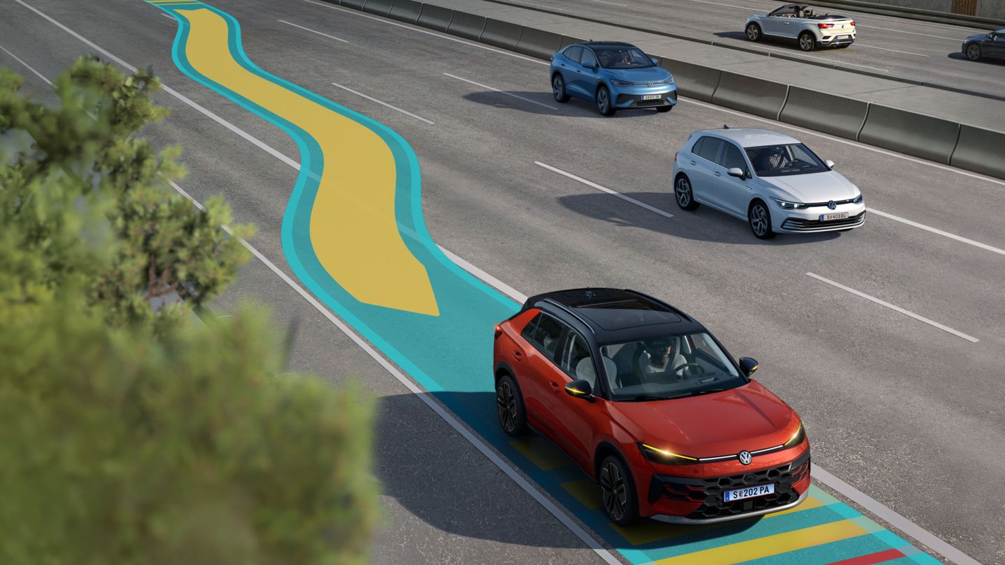 Automobil jazdí po diaľnici v pruhu označenom farebnými čiarami. Okolo sú ďalšie automobily. Pri ceste sú chrániace betónové zátarasy.