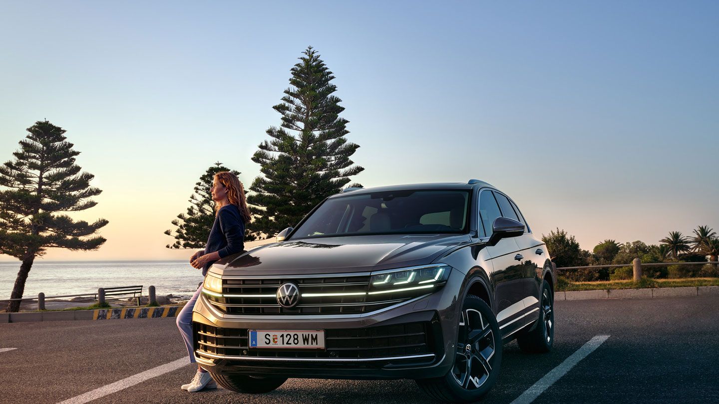 VW Touareg Elegance za súmraku pri mori so zapnutými svetlometmi HD Matrix. 