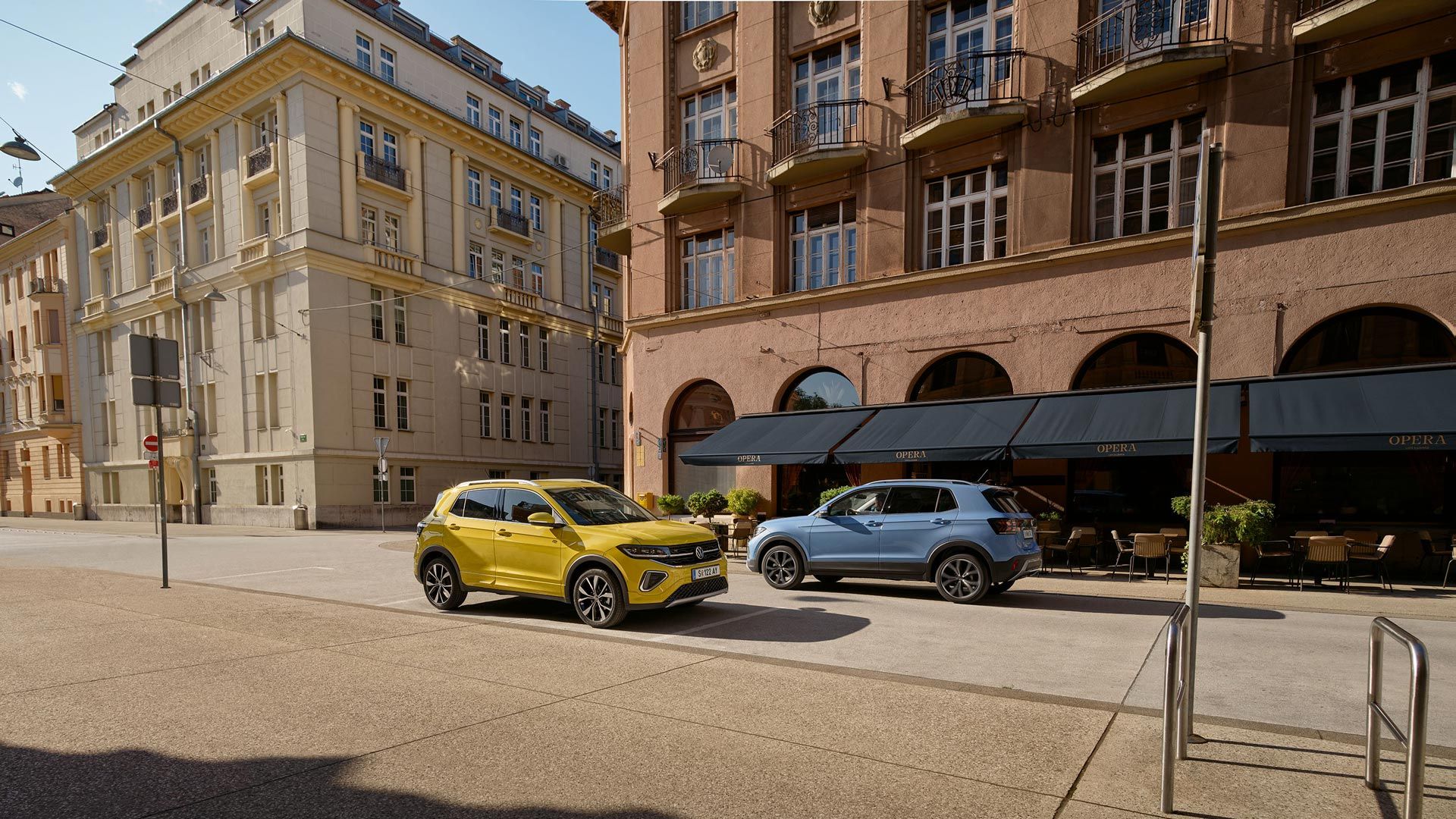 Po ulici idú okolo seba žltý a modrý VW T-Cross.
