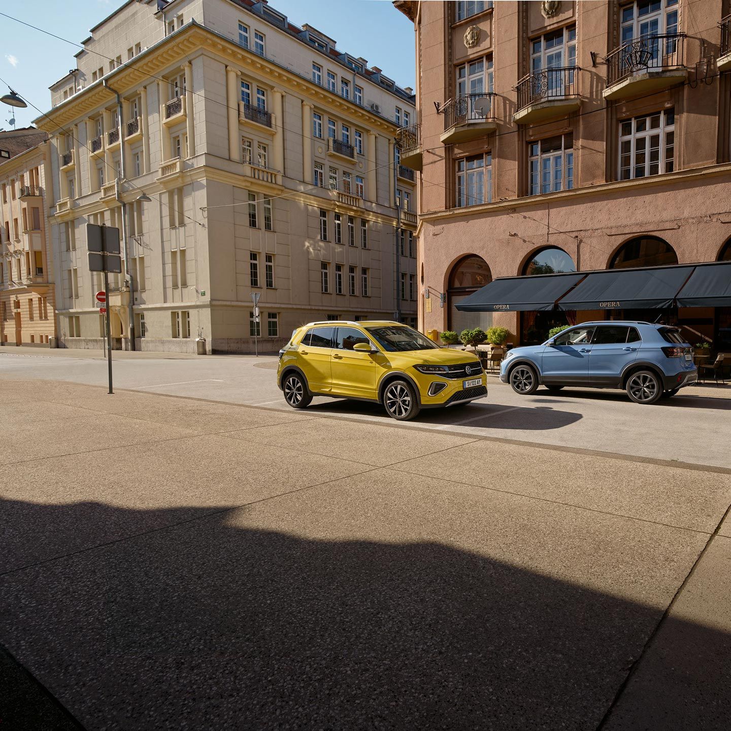 Po ulici idú okolo seba žltý a modrý VW T-Cross.