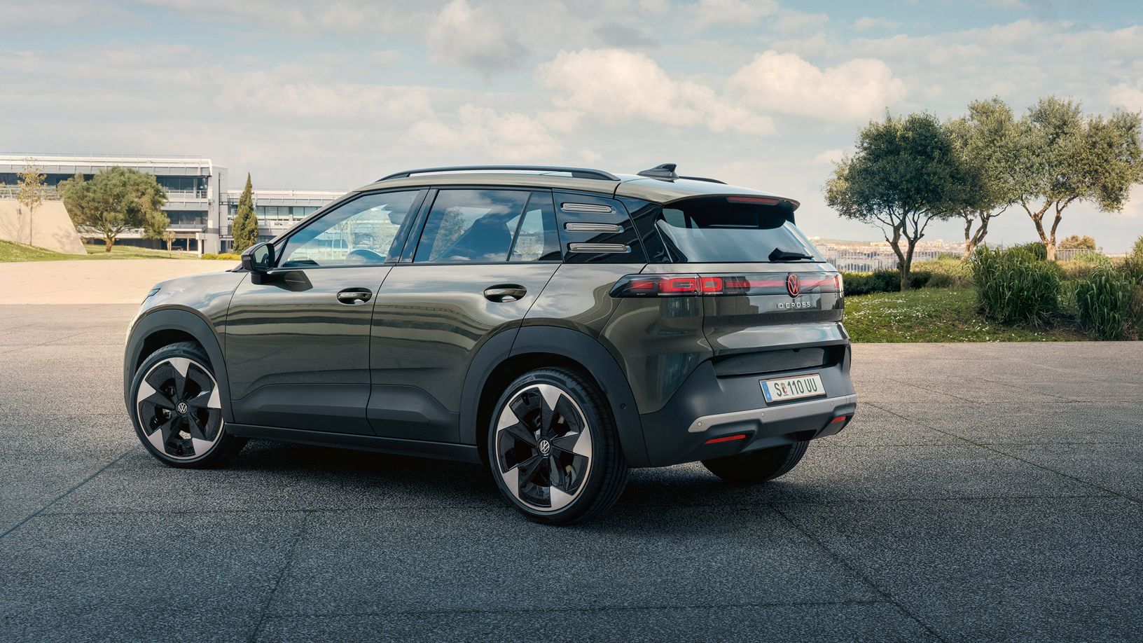 Pohľad zozadu na zelené VW ID. Cross zaparkované na námestí so zelenými stromami.