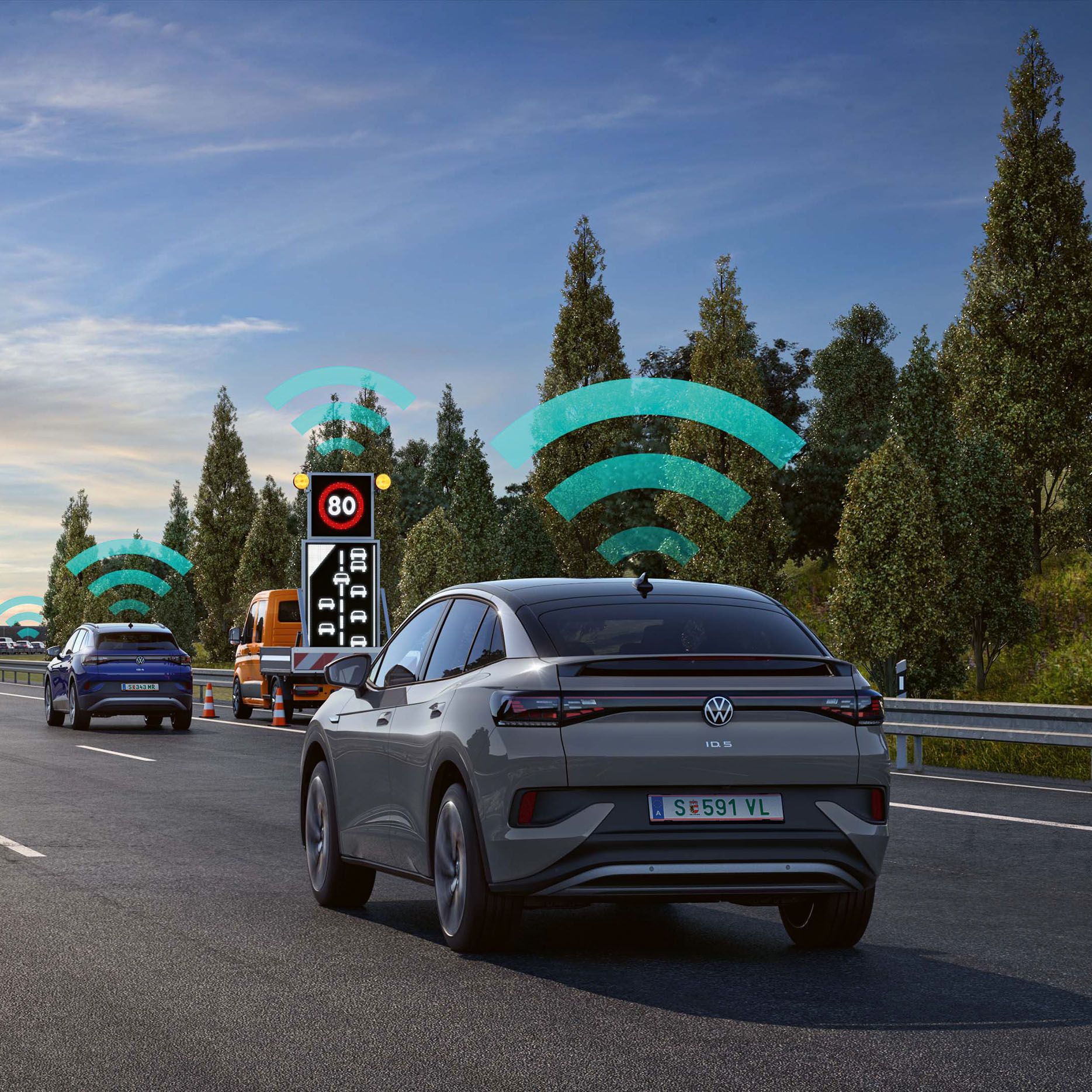 Na obrázku je diaľnica so štyrmi pruhmi a niekoľkými automobilmi.  Nad vozidlami je graficky zobrazená ikona WiFi, ktorá znázorňuje vzájomné prepojenie vozidiel a systém Varovania pred nebezpečenstvom. 