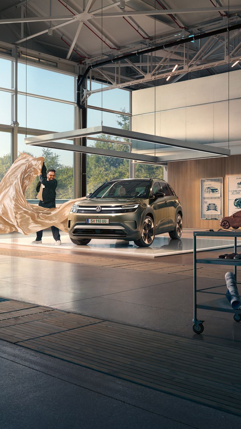 Muž vytiahne veľkú látku zo zeleného VW ID. Cross, ktorý stojí v minimalistickom dizajnérskom štúdiu.