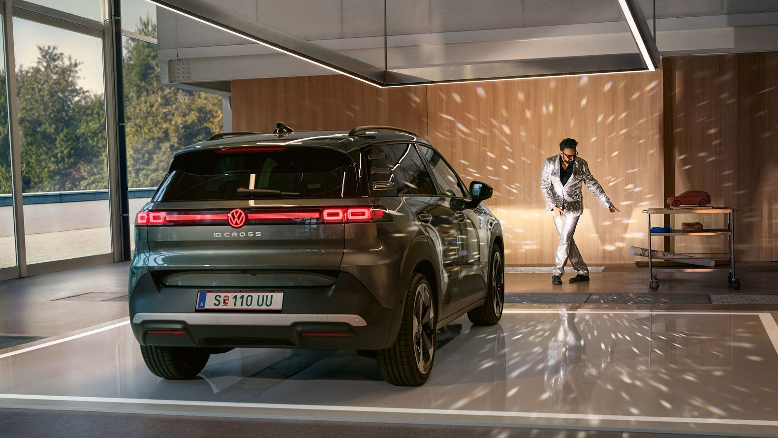 VW ID. Cross stojí v showroome so zapnutými svetlami a osvetľuje tancujúcího muža v trblietavom obleku.