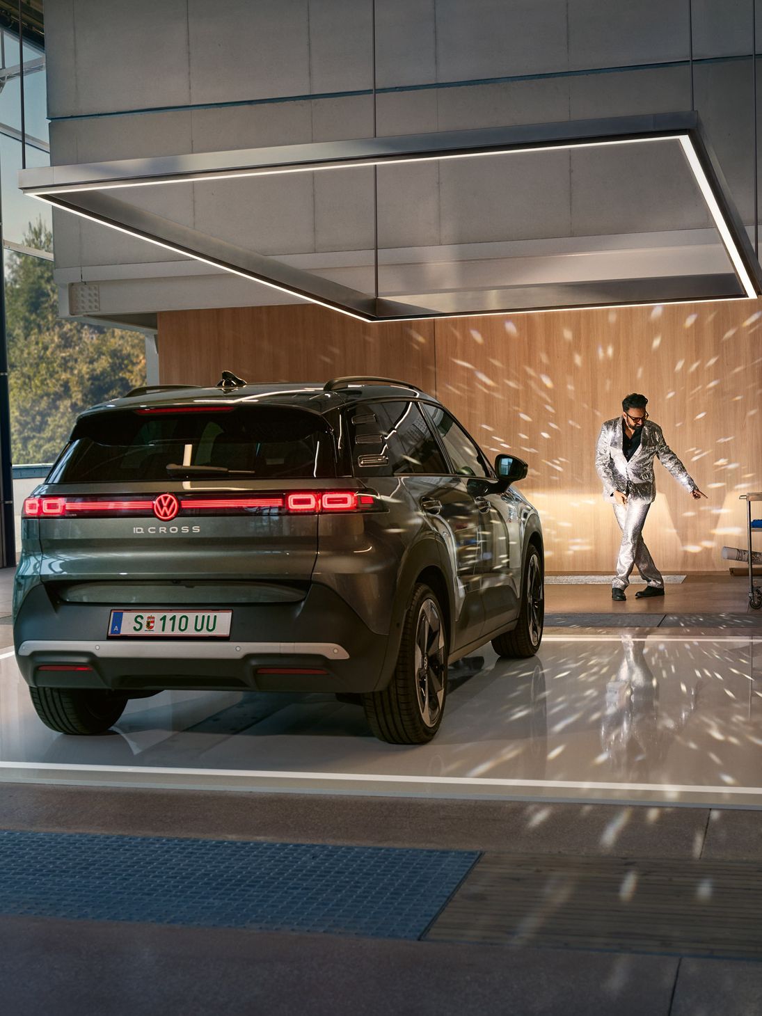 VW ID. Cross stojí v showroome so zapnutými svetlami a osvetľuje tancujúcího muža v trblietavom obleku.