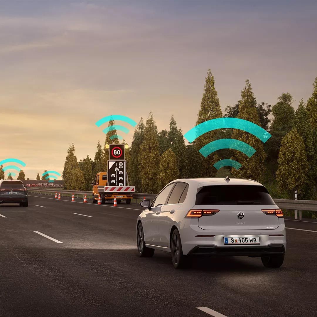 Vozidlo VW Golf jazdí v jazdnom pruhu na diaľnici. Nad autom sú ikony znázorňujúce pripojenie na internet. V pozadí je nákladné auto a stromy.