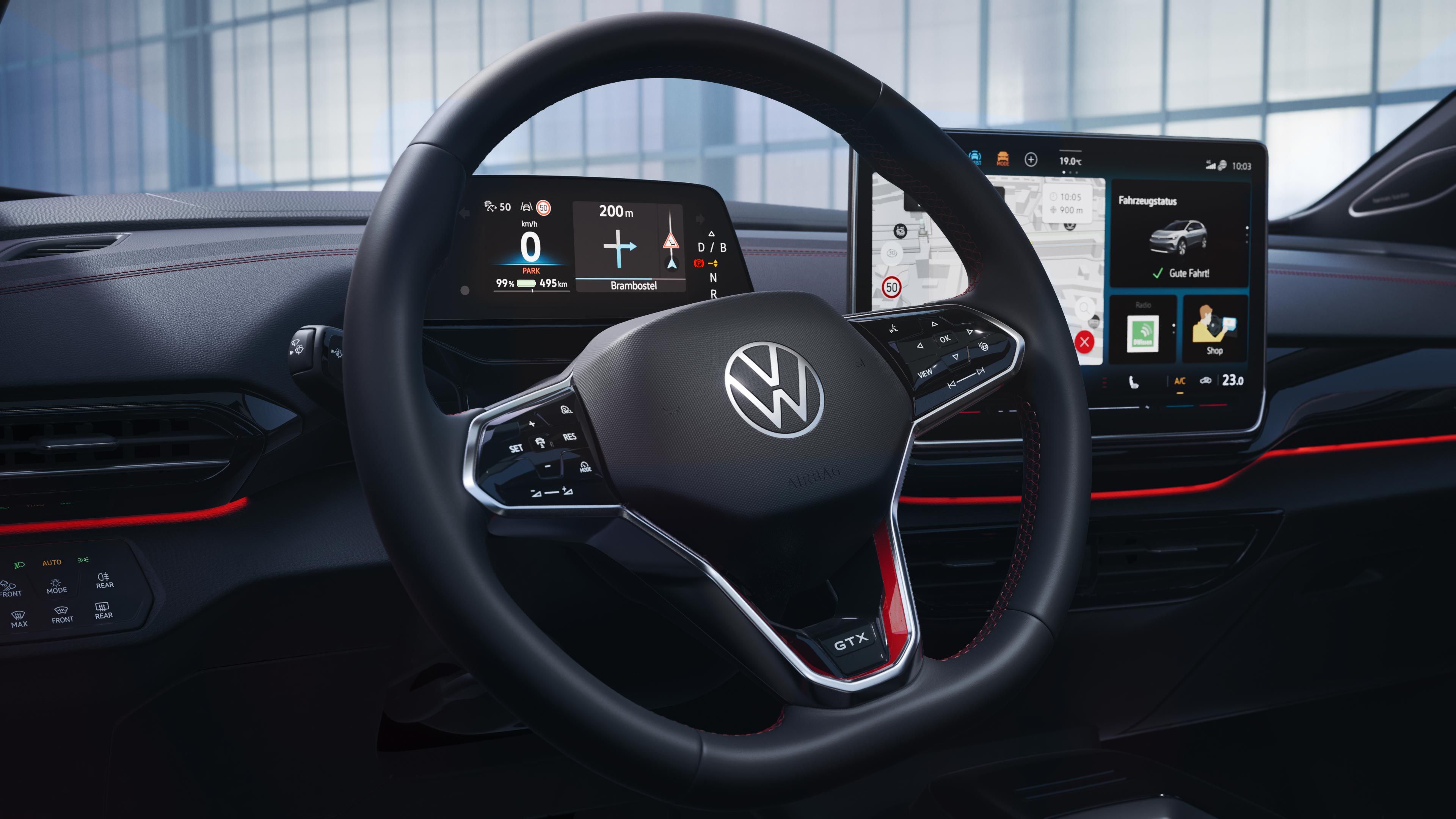 VW ID.4 GTX interiér. Pohľad na multifunkčný volant, digitálny prístrojový panel, palubnú dosku a displej systému infotainment integrovaný v nej. Ambientné osvetlenie v červenom odtieni vytvára zaujímavú atmosféru.