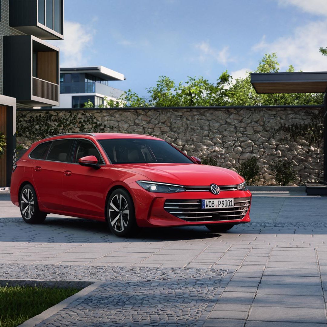 Červený VW Passat stojí na parkovisku pri modernom bytovom dome. Vozidlo je zaparkované na dlažobných kockách.