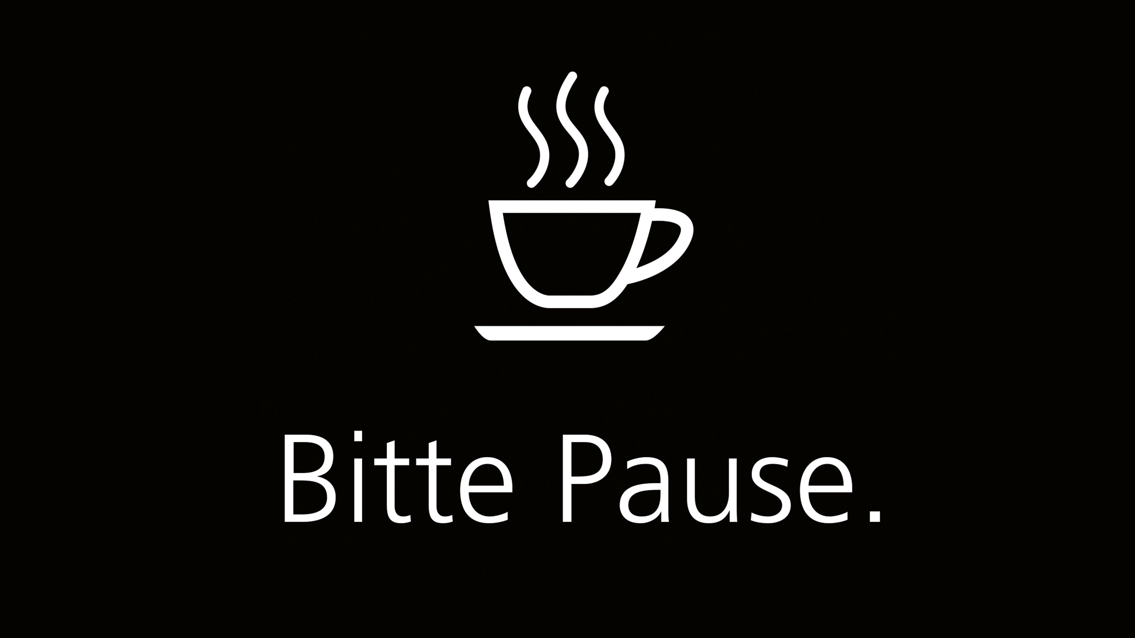 Ikona šálky kávy s tromi stúpajúcimi parnými líniami. Pod šálkou je nápis "Bitte Pause" (Prosím prestávka). Pozadie je čierne.