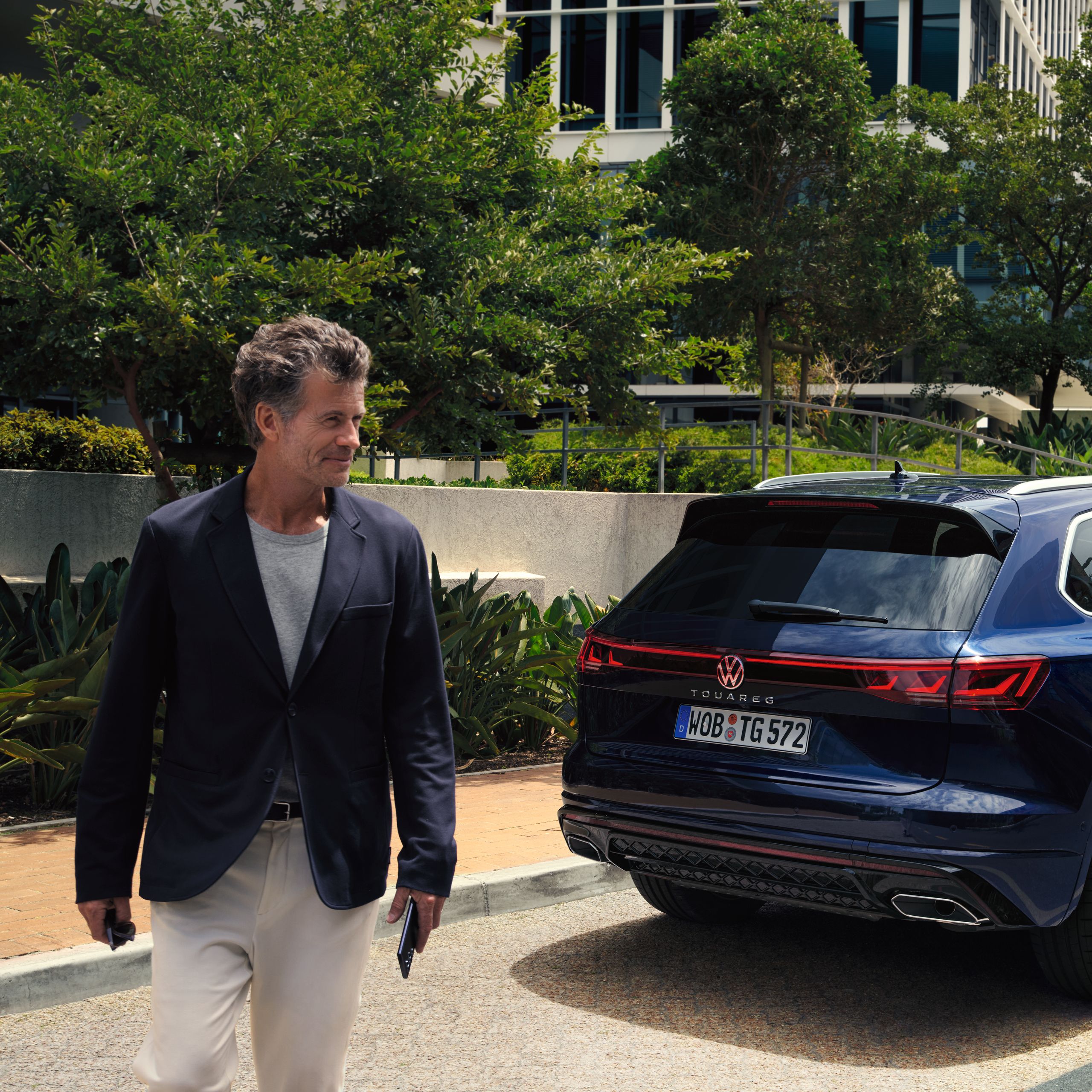 Muž kráča od svojho v meste zaparkovaného vozidla Volkswagen Touareg.